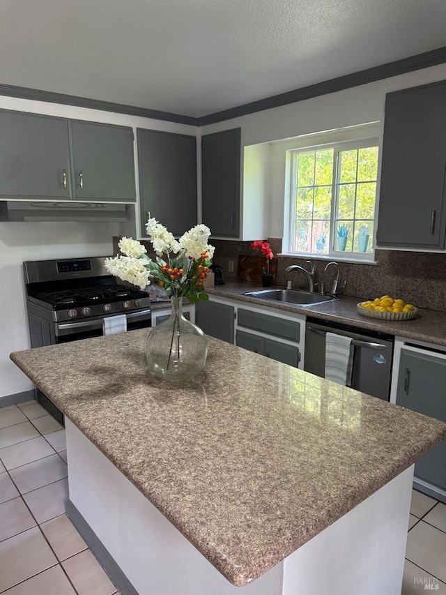 kitchen featuring tasteful backsplash, under cabinet range hood, stainless steel gas stove, a sink, and dishwasher