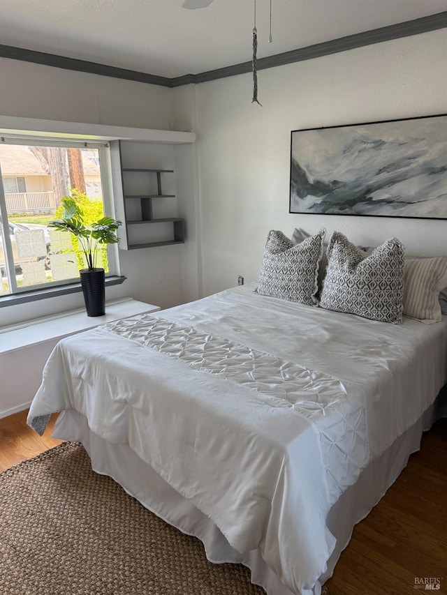 bedroom featuring wood finished floors and crown molding