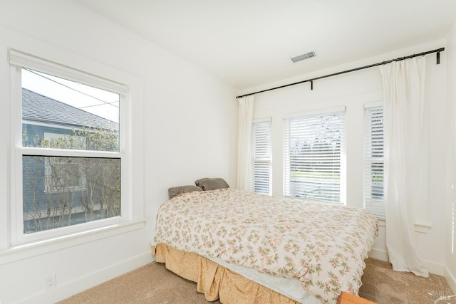 bedroom featuring visible vents, multiple windows, and light carpet