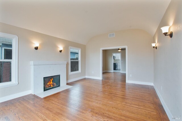 308 Central Ave, Vallejo, CA 94590 - unfurnished living room featuring visible vents, a fireplace with flush hearth, vaulted ceiling, and light wood-type flooring