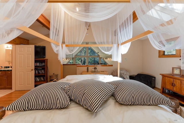 bedroom with lofted ceiling with beams and multiple windows