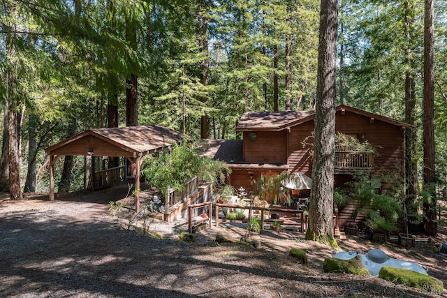 exterior space with a carport, a wooded view, and stairway