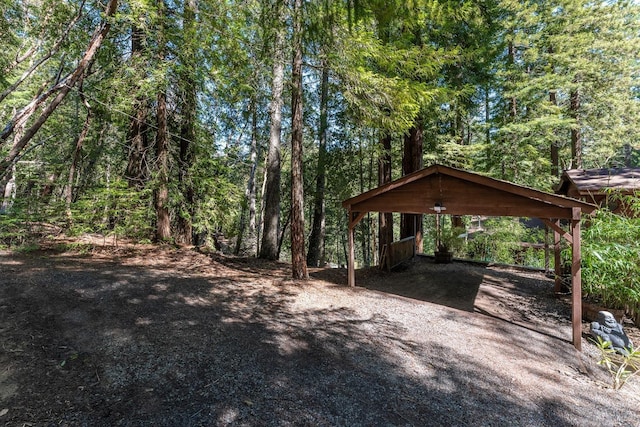 view of yard featuring a wooded view, driveway, and a detached carport