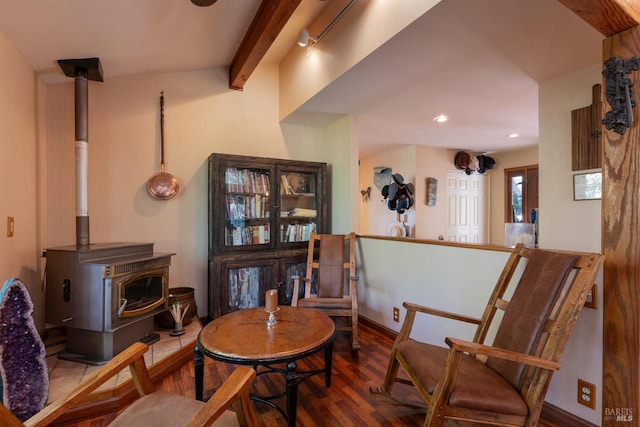 living area featuring recessed lighting, a wood stove, baseboards, beamed ceiling, and wood finished floors