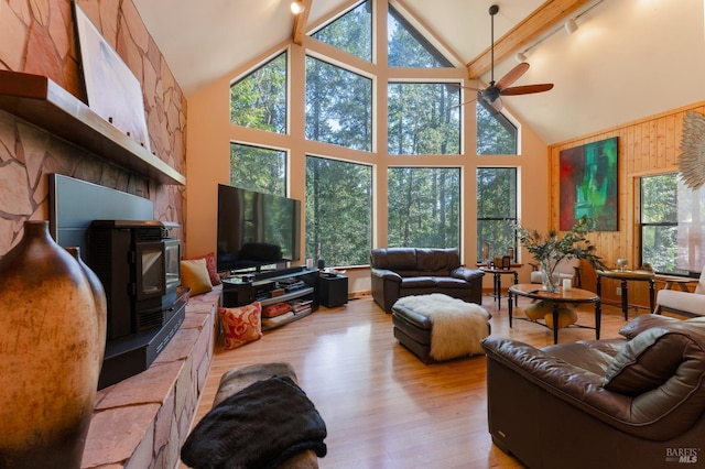 living area featuring rail lighting, high vaulted ceiling, wooden walls, a ceiling fan, and wood finished floors