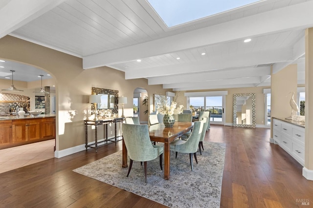 dining space with beamed ceiling, baseboards, recessed lighting, arched walkways, and wood-type flooring