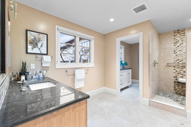 bathroom with tiled shower, vanity, baseboards, visible vents, and recessed lighting