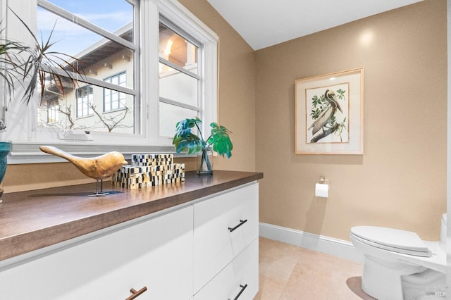 bathroom featuring toilet, vanity, and baseboards
