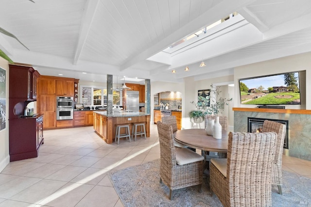 dining area featuring light tile patterned flooring, beam ceiling, a tile fireplace, a skylight, and recessed lighting