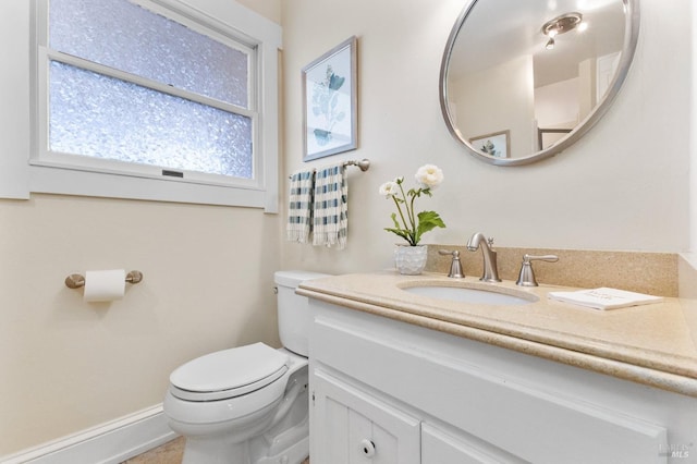 half bath featuring toilet, vanity, and baseboards