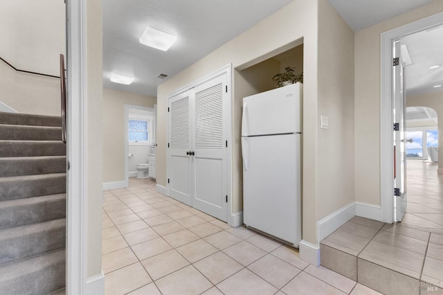 hall with baseboards, stairway, and light tile patterned floors