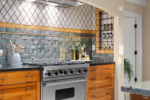 kitchen with decorative backsplash, stainless steel stove, and dark stone counters