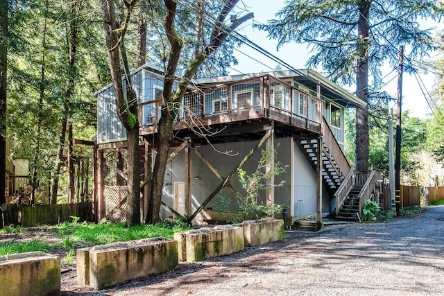 exterior space with stairs, gravel driveway, and fence