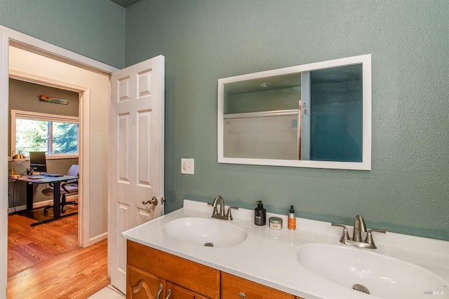 full bath featuring double vanity, a sink, and wood finished floors