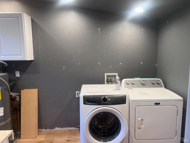 clothes washing area featuring light wood finished floors, washing machine and dryer, and a textured wall