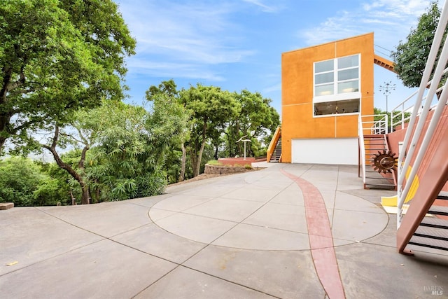 view of patio / terrace featuring driveway, stairs, and a garage