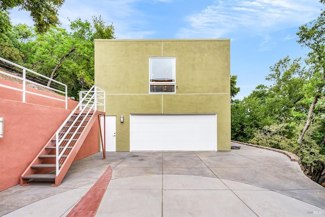 exterior space featuring stucco siding, an attached garage, stairway, and concrete driveway