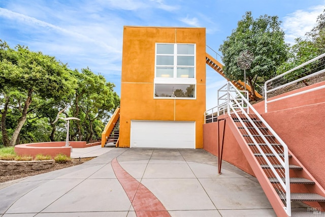 exterior space featuring stucco siding, concrete driveway, stairs, and a garage