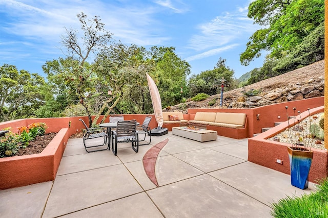 view of patio with outdoor dining area and an outdoor living space with a fire pit