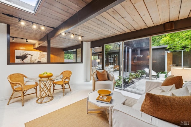 living area with rail lighting, wood ceiling, a skylight, and beam ceiling