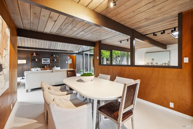 carpeted dining space featuring wooden walls, wooden ceiling, and beam ceiling