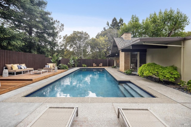view of swimming pool with an outdoor hangout area, a wooden deck, a fenced backyard, a fenced in pool, and a patio area