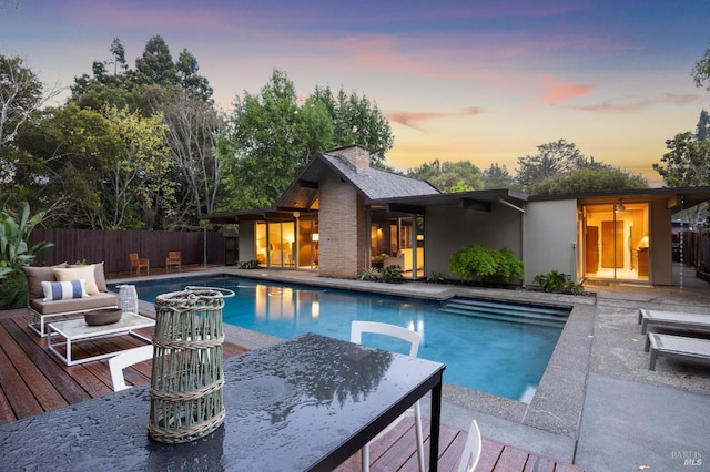 view of swimming pool with outdoor dining area, a wooden deck, fence, and a fenced in pool