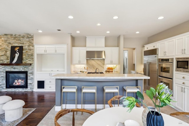 5232 Sunridge Dr, Fairfield, CA 94534 - kitchen featuring built in appliances, under cabinet range hood, white cabinetry, recessed lighting, and wood finished floors