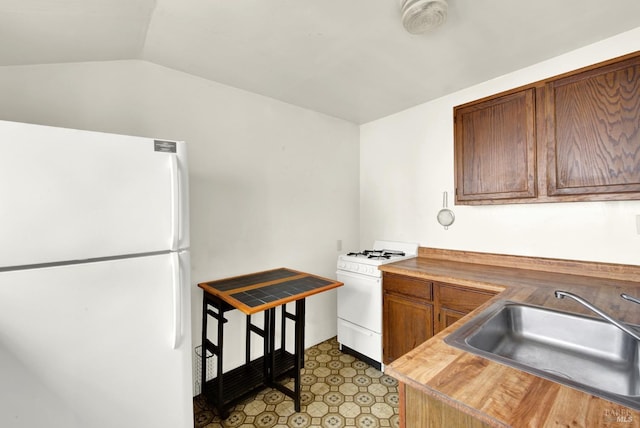 kitchen with vaulted ceiling, a sink, light floors, wooden counters, and white appliances