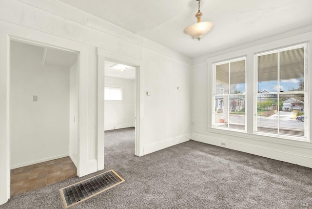 empty room with baseboards, visible vents, and carpet flooring