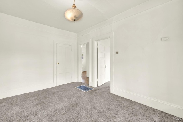carpeted spare room featuring baseboards and visible vents