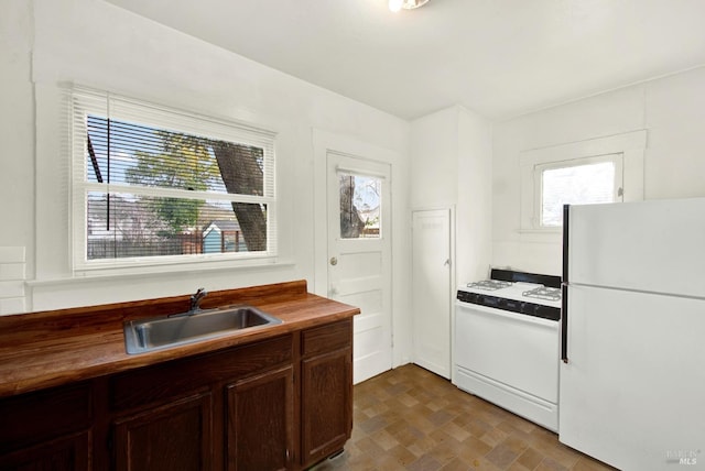kitchen featuring butcher block countertops, a sink, and white appliances