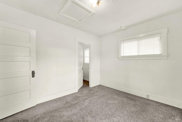 unfurnished bedroom with carpet flooring, baseboards, and attic access