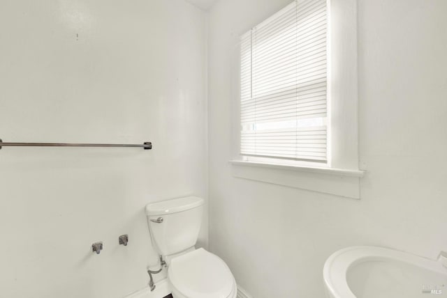 half bath with toilet, a sink, and baseboards