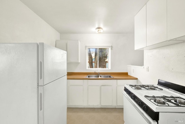 kitchen featuring white cabinetry, light tile patterned floors, a sink, and white appliances