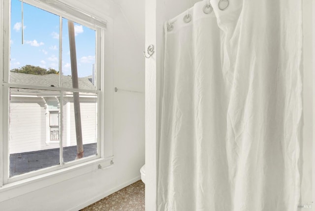 full bathroom featuring baseboards, toilet, and curtained shower