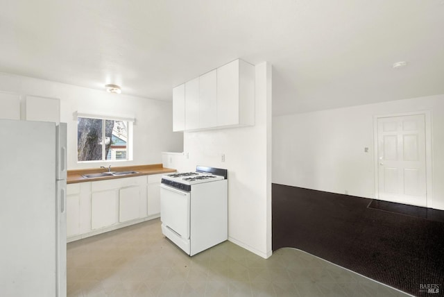 kitchen with white appliances, white cabinets, light floors, and a sink