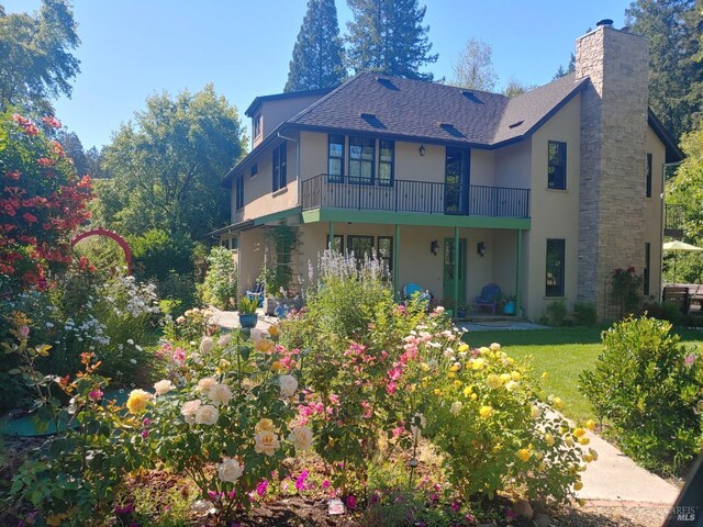 11900 Hwy 116, Guerneville, CA 95446 - back of house featuring a shingled roof, stucco siding, a chimney, a balcony, and a yard