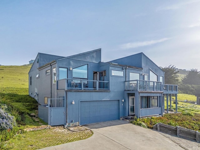 modern home with driveway, an attached garage, and a balcony