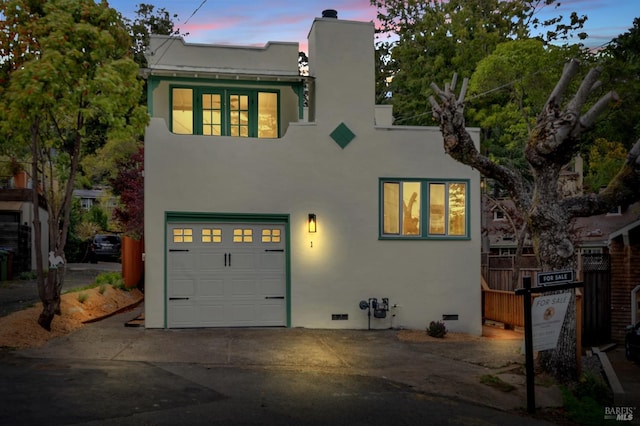 view of front of home featuring stucco siding, an attached garage, driveway, crawl space, and a chimney