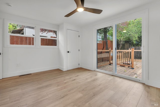 unfurnished room featuring baseboards, visible vents, wood finished floors, and ceiling fan