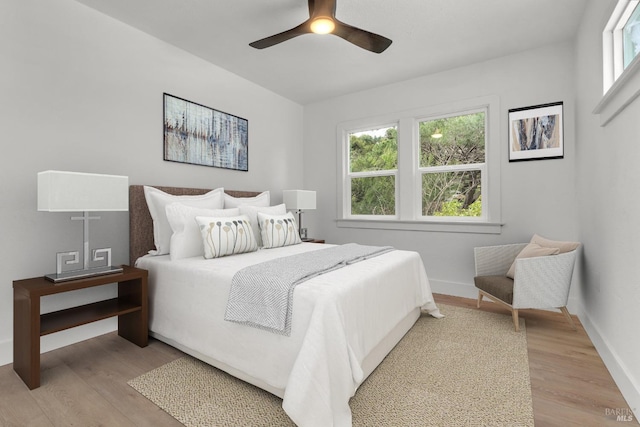 bedroom featuring baseboards, multiple windows, and light wood-type flooring