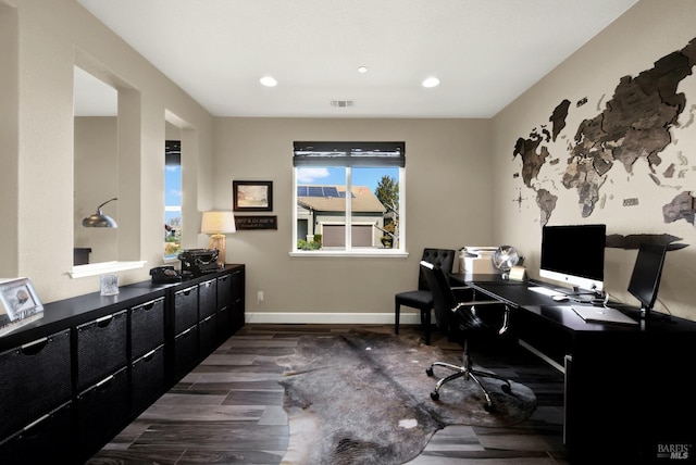 office space featuring dark wood-type flooring, baseboards, visible vents, and a wealth of natural light