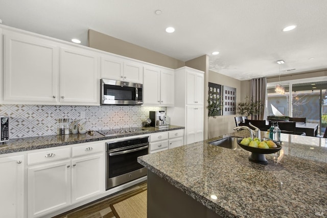 kitchen featuring stainless steel appliances, a sink, recessed lighting, white cabinetry, and decorative backsplash