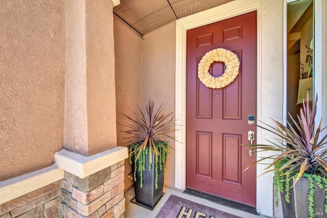 property entrance featuring covered porch and stucco siding