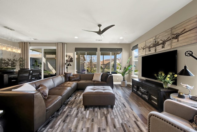 living area featuring ceiling fan with notable chandelier, wood finished floors, recessed lighting, and a healthy amount of sunlight