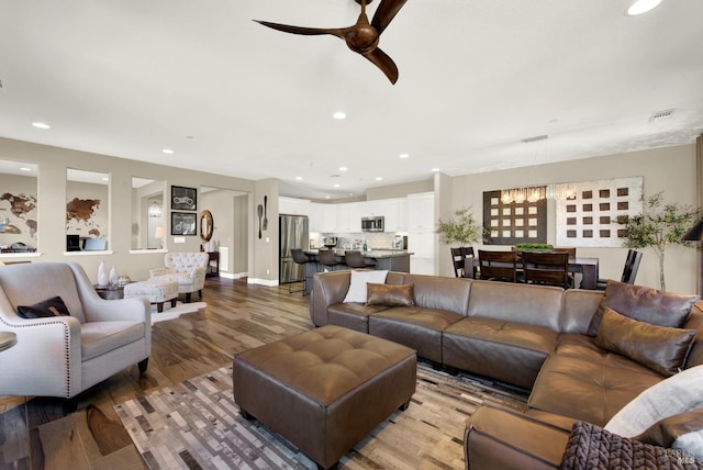 living area with ceiling fan with notable chandelier, wood finished floors, visible vents, and recessed lighting