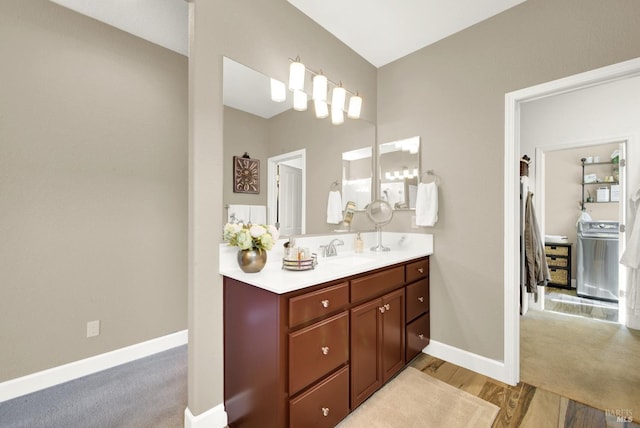 bathroom with baseboards, washer / clothes dryer, vanity, and wood finished floors