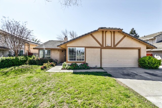 view of front of home featuring an attached garage, a chimney, concrete driveway, a front yard, and stucco siding