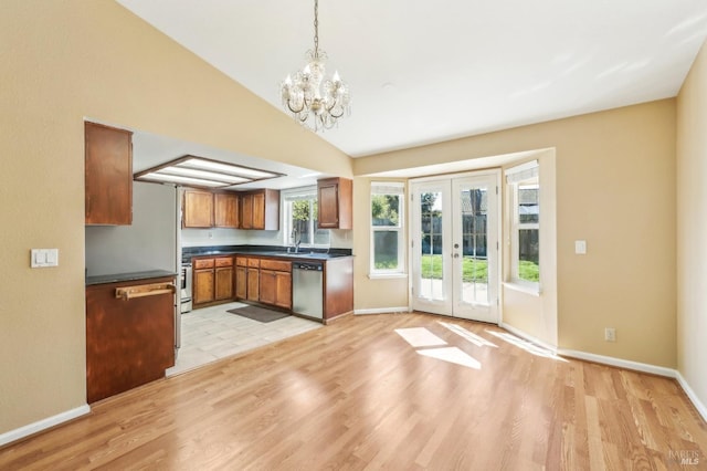 kitchen featuring french doors, stainless steel appliances, a sink, dark countertops, and a notable chandelier